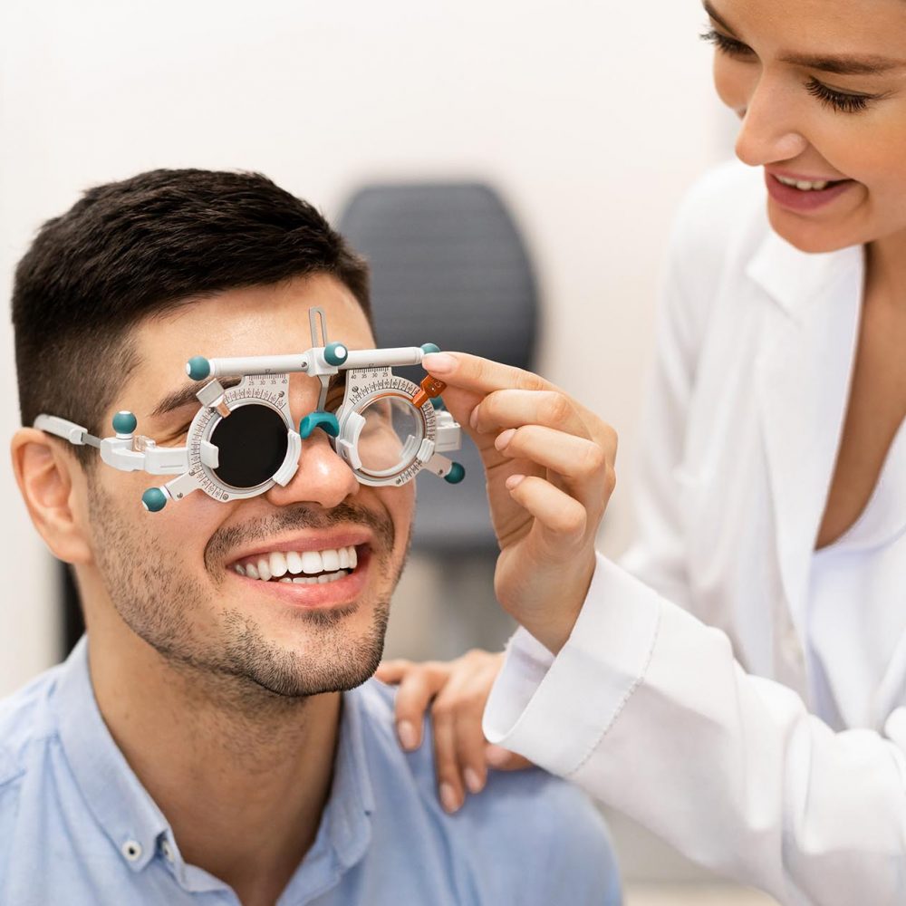 Consultation With The Ophthalmologist Concept. Portrait of woman optometrist examining eyesight of male client with trial frame and closed eye. Woman doing checkup of man's eye with diagnostic tool